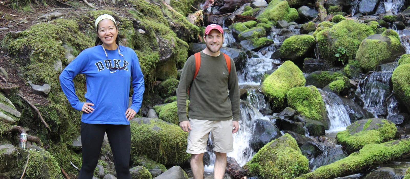 two students in front of waterfall