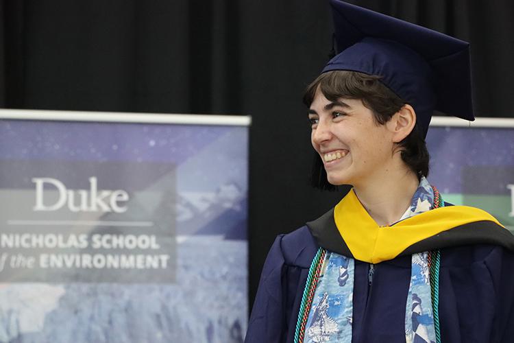 Catalina in academic regalia in front of Nicholas School banner