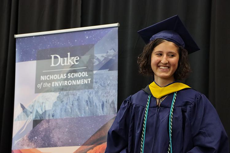 Abigail Saks in academic regalia in front of Nicholas School banner