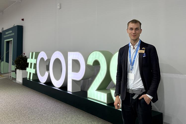 Dima in front of #COP29 sign