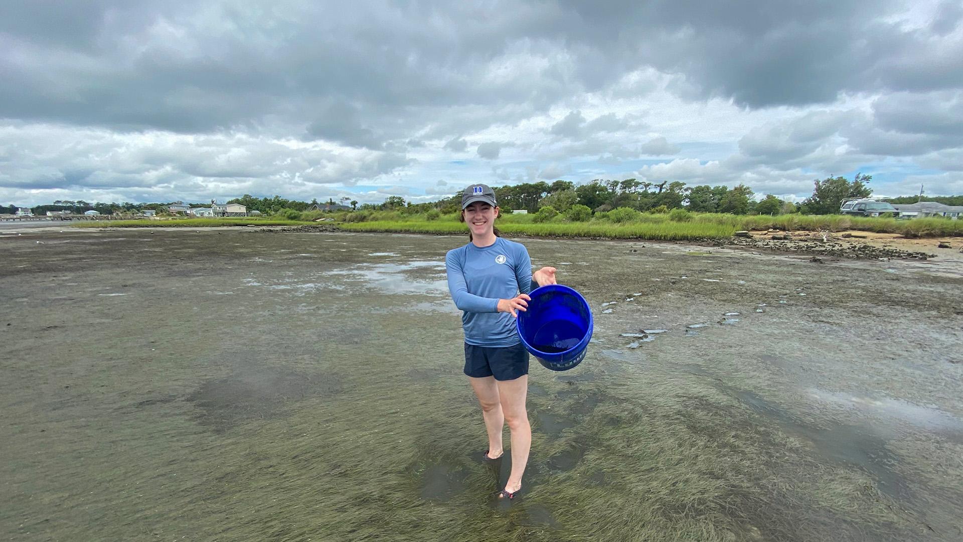 Chloe holding bucket in shallow water