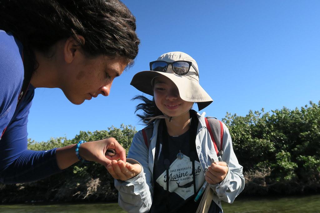 student with hat showing marine animal in hand