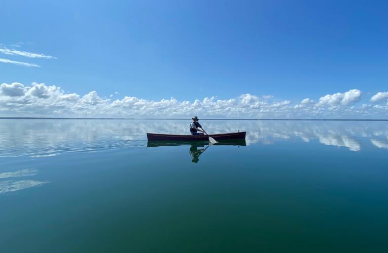 silhouette of one person in canoe on water