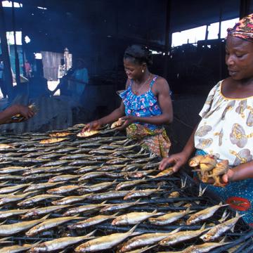 women cooking fish on open flame