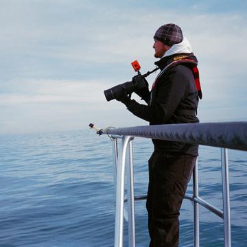 Greg on boat looks for humpback whales off Virginia Beach, VA to photograph