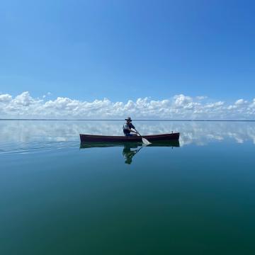 silhouette of one person in canoe on water