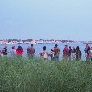 Event participants stand around at dusk at Duke Marine Lab